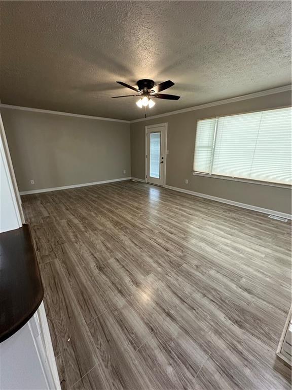 3967 Evelyn Dr, Powder Springs, GA 30127 - unfurnished living room featuring baseboards, ceiling fan, ornamental molding, wood finished floors, and a textured ceiling