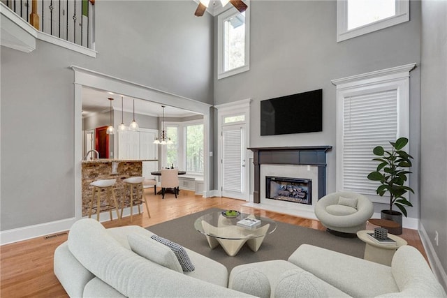 3085 Woodbridge Ln, Canton, GA 30114 - living room with a high ceiling, baseboards, a fireplace with flush hearth, wood finished floors, and a ceiling fan