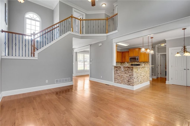 3085 Woodbridge Ln, Canton, GA 30114 - kitchen with stainless steel microwave, backsplash, ornamental molding, hanging light fixtures, and light wood-style flooring