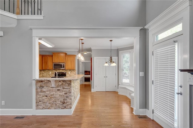 3085 Woodbridge Ln, Canton, GA 30114 - kitchen featuring stainless steel microwave, tasteful backsplash, ornamental molding, pendant lighting, and light wood finished floors