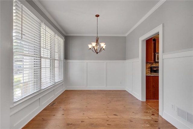 3085 Woodbridge Ln, Canton, GA 30114 - unfurnished dining area featuring a chandelier, crown molding, wood finished floors, a decorative wall, and wainscoting
