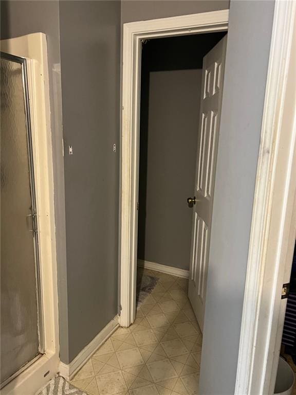 full bathroom with tile patterned flooring, a shower stall, and baseboards