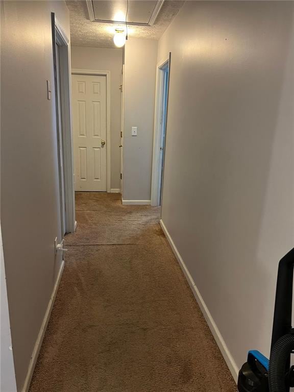 hall featuring carpet flooring, attic access, and baseboards