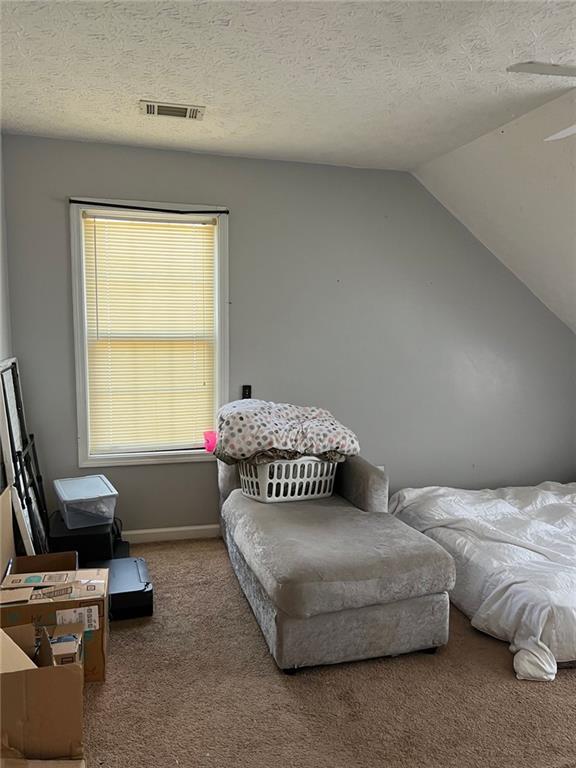 carpeted bedroom featuring vaulted ceiling, a textured ceiling, visible vents, and baseboards