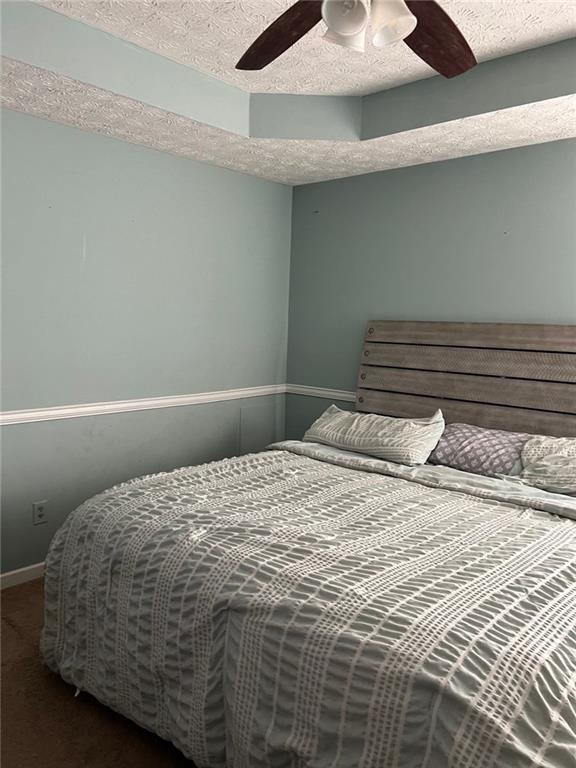 bedroom featuring a textured ceiling, carpet floors, a ceiling fan, and baseboards