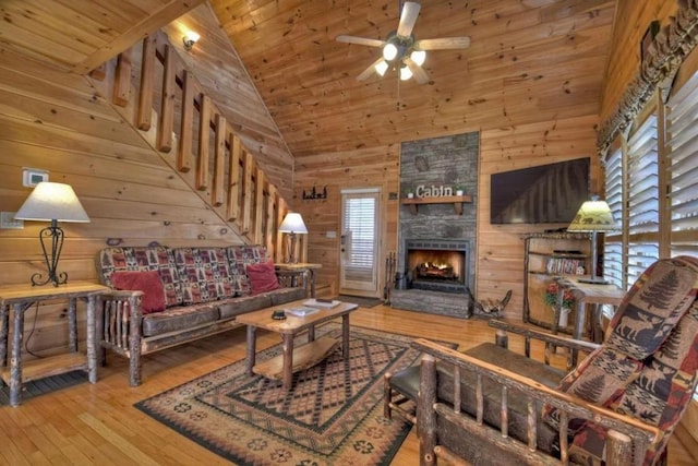 living room featuring wood ceiling, a stone fireplace, high vaulted ceiling, wood walls, and hardwood / wood-style flooring