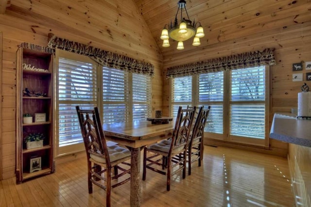 dining room featuring wood walls, plenty of natural light, and light hardwood / wood-style flooring