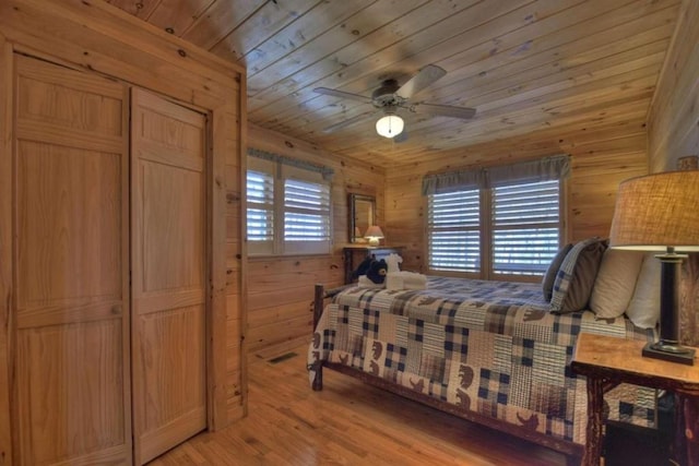 bedroom with wooden walls, ceiling fan, hardwood / wood-style floors, and multiple windows