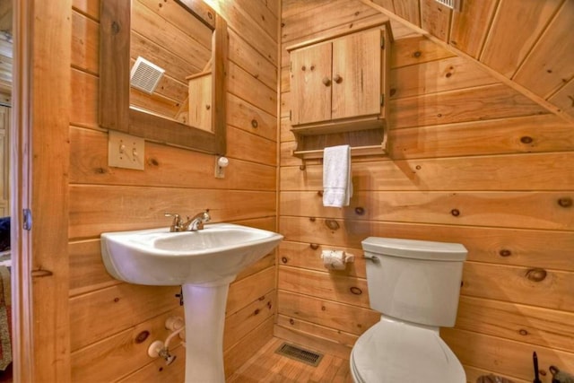 bathroom with wood walls and toilet