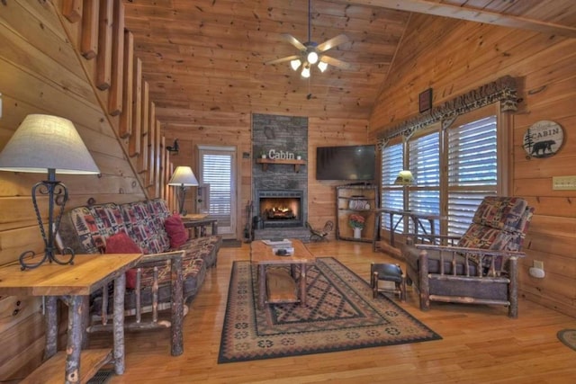 living room with hardwood / wood-style flooring, ceiling fan, a healthy amount of sunlight, and a stone fireplace