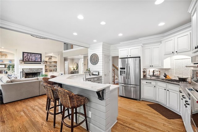 1235 Grand View Dr SE, Smyrna, GA 30126 - kitchen with appliances with stainless steel finishes, crown molding, open floor plan, a kitchen bar, and a stone fireplace