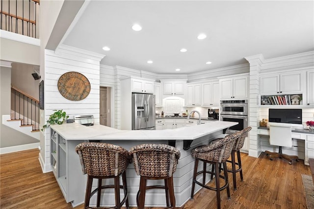 1235 Grand View Dr SE, Smyrna, GA 30126 - kitchen featuring stainless steel appliances, a kitchen bar, white cabinetry, a peninsula, and wood finished floors