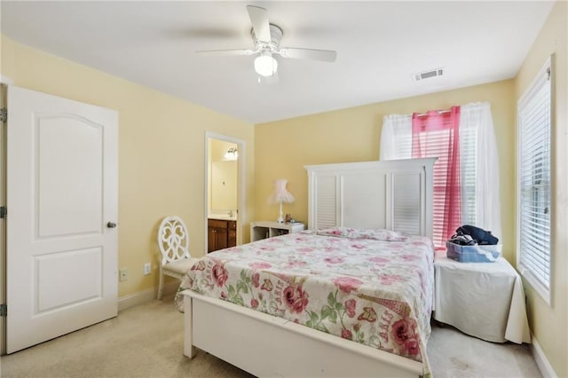 bedroom featuring ceiling fan, light colored carpet, and connected bathroom