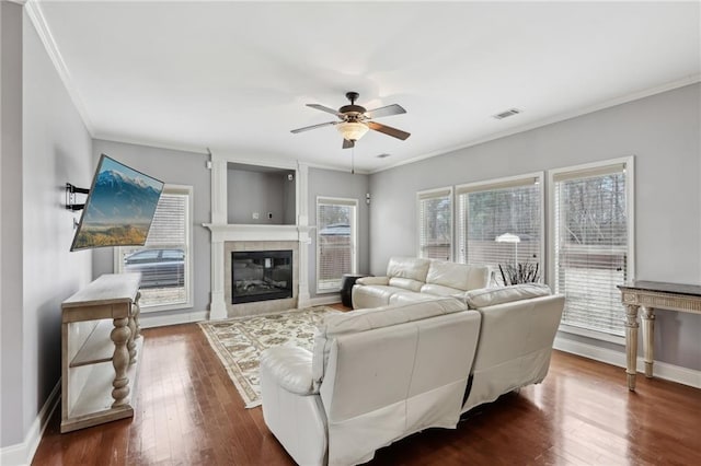 living room with a fireplace, ornamental molding, dark hardwood / wood-style floors, and ceiling fan