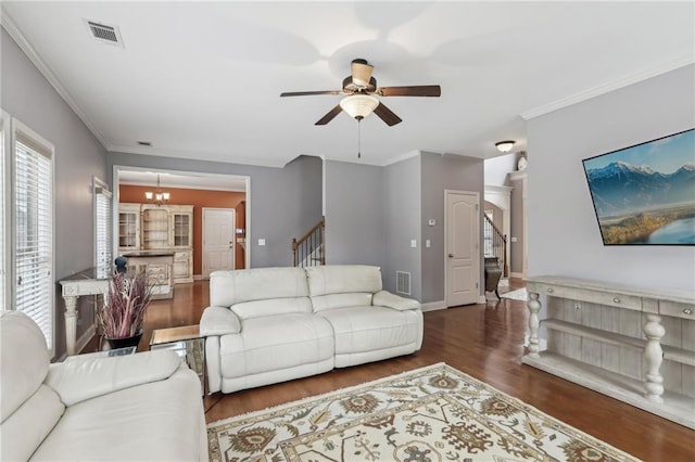 living room with dark hardwood / wood-style flooring, crown molding, and ceiling fan with notable chandelier