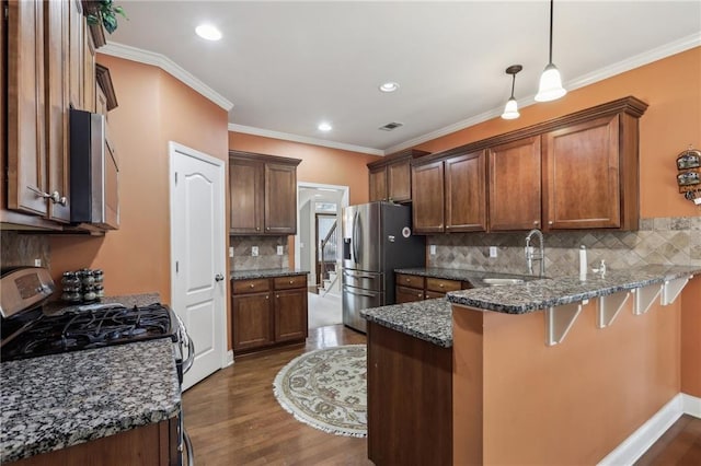 kitchen featuring sink, dark stone countertops, hanging light fixtures, kitchen peninsula, and stainless steel appliances