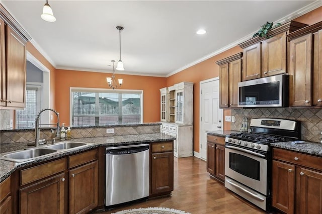 kitchen featuring sink, crown molding, hardwood / wood-style flooring, hanging light fixtures, and stainless steel appliances