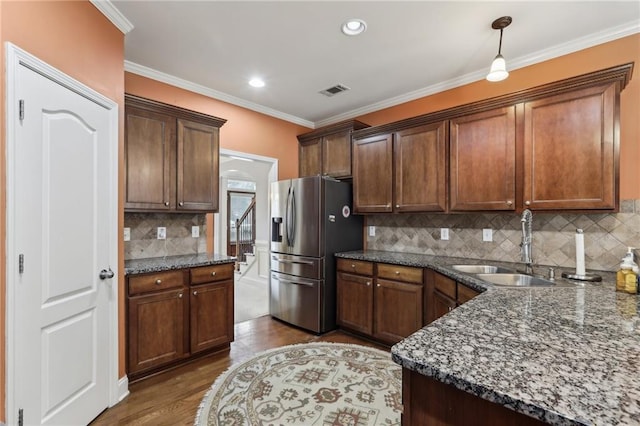 kitchen featuring pendant lighting, sink, hardwood / wood-style flooring, stainless steel refrigerator with ice dispenser, and dark stone counters