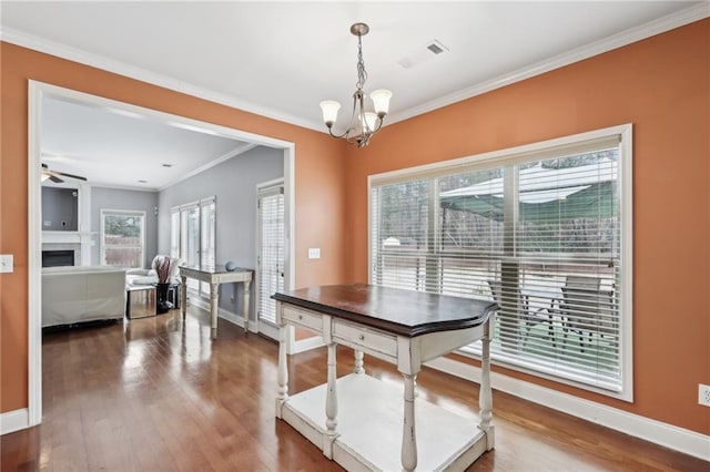 dining room with wood-type flooring, ceiling fan with notable chandelier, and crown molding