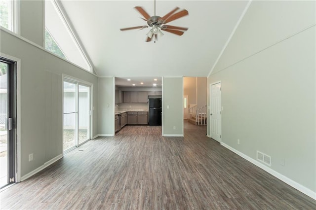 unfurnished living room with high vaulted ceiling, visible vents, dark wood finished floors, ceiling fan, and baseboards