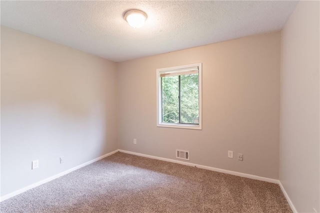 spare room with a textured ceiling, baseboards, visible vents, and carpet floors