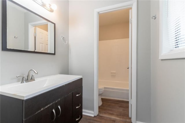 bathroom with toilet, vanity, and wood finished floors