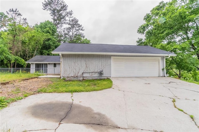 garage featuring driveway and fence