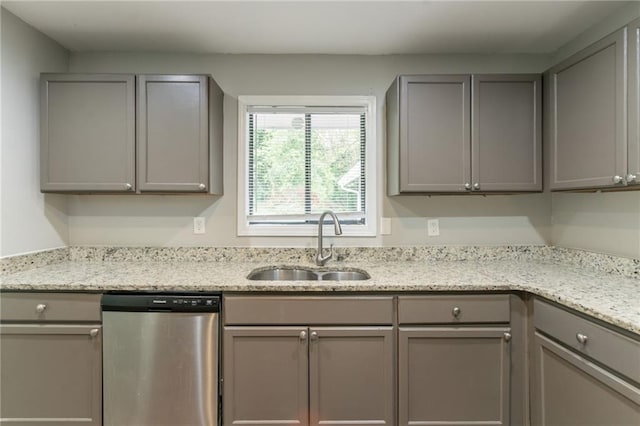 kitchen with dishwasher, gray cabinets, light stone countertops, and a sink