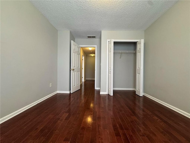 unfurnished bedroom featuring dark hardwood / wood-style flooring, a closet, and a textured ceiling