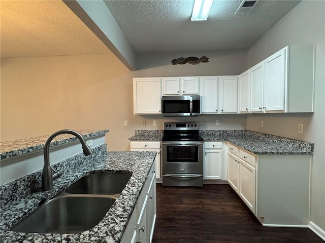 kitchen with sink, appliances with stainless steel finishes, dark hardwood / wood-style floors, light stone countertops, and white cabinets