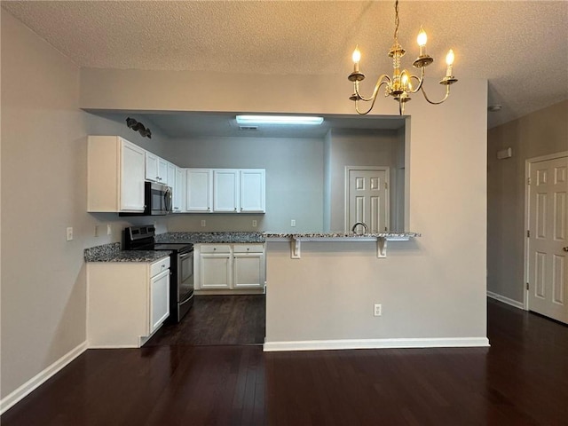 kitchen featuring stainless steel appliances, white cabinetry, light stone countertops, and pendant lighting