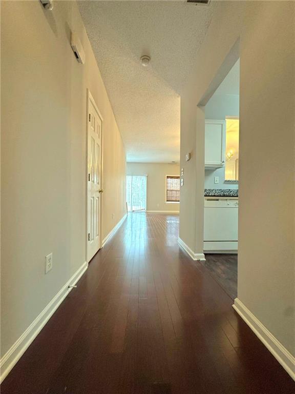 unfurnished living room featuring ceiling fan with notable chandelier, dark hardwood / wood-style floors, and a textured ceiling