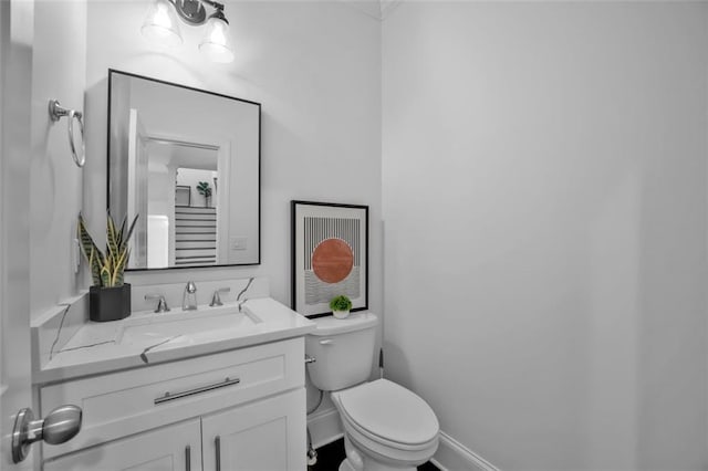 half bath with vanity, toilet, and baseboards