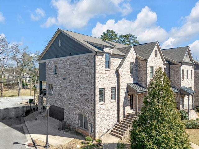 view of property exterior with concrete driveway, brick siding, and a patio area