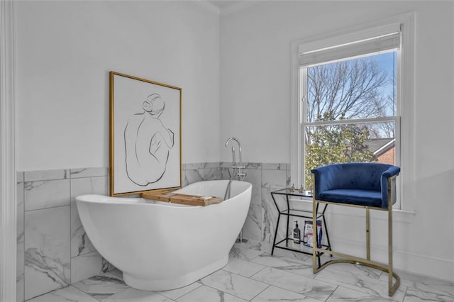 bathroom featuring marble finish floor, tile walls, a soaking tub, and wainscoting