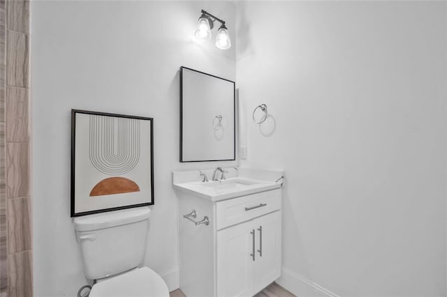 bathroom featuring baseboards, vanity, and toilet