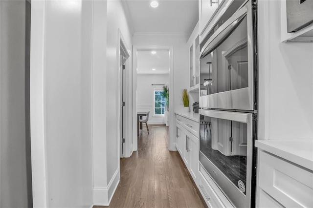 hallway featuring recessed lighting, wood finished floors, and crown molding