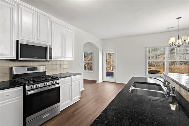 kitchen with hanging light fixtures, stainless steel appliances, an inviting chandelier, white cabinets, and sink