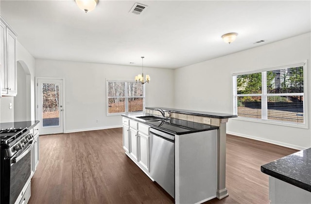 kitchen with appliances with stainless steel finishes, dark hardwood / wood-style flooring, white cabinets, decorative light fixtures, and sink