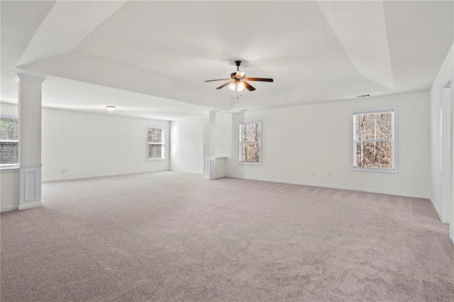 unfurnished room with light carpet, ceiling fan, a tray ceiling, and plenty of natural light