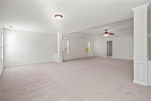 carpeted spare room featuring ornate columns and ceiling fan