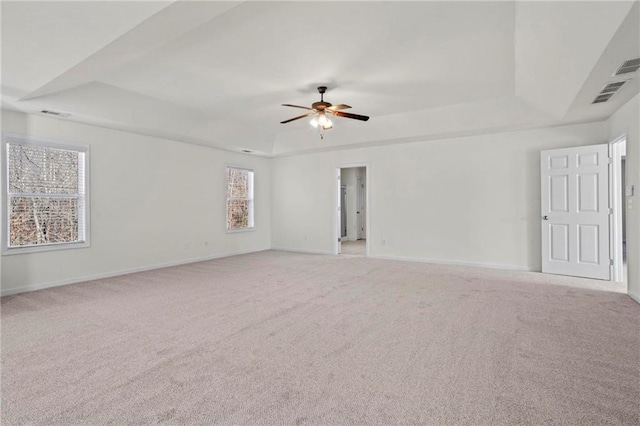 spare room featuring light colored carpet, ceiling fan, and a tray ceiling