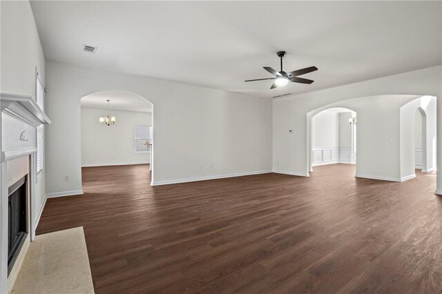 unfurnished living room with ceiling fan with notable chandelier and dark hardwood / wood-style floors