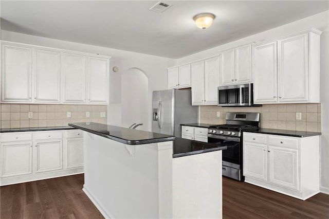 kitchen featuring stainless steel appliances, a center island, dark wood-type flooring, decorative backsplash, and white cabinets