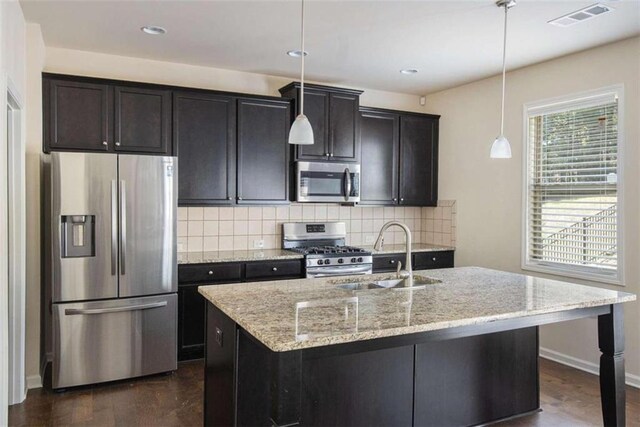 kitchen with a center island with sink, dark hardwood / wood-style flooring, stainless steel appliances, sink, and decorative light fixtures