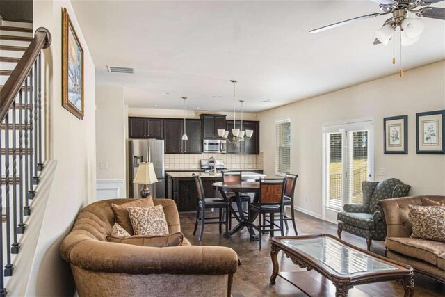 living room featuring ceiling fan with notable chandelier