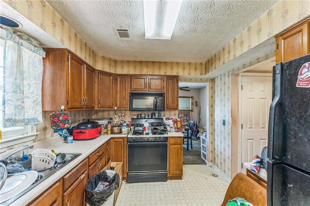 4945 Penscot Way, Stone Mountain, GA 30088 - kitchen with black appliances, light flooring, wallpapered walls, light countertops, and brown cabinetry