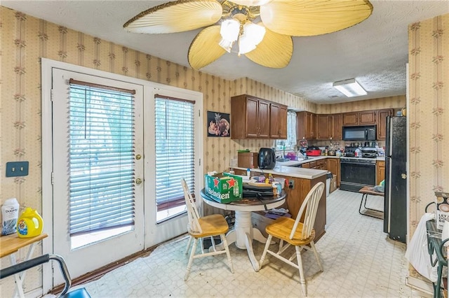 4945 Penscot Way, Stone Mountain, GA 30088 - kitchen featuring wallpapered walls, black appliances, light countertops, a peninsula, and a textured ceiling