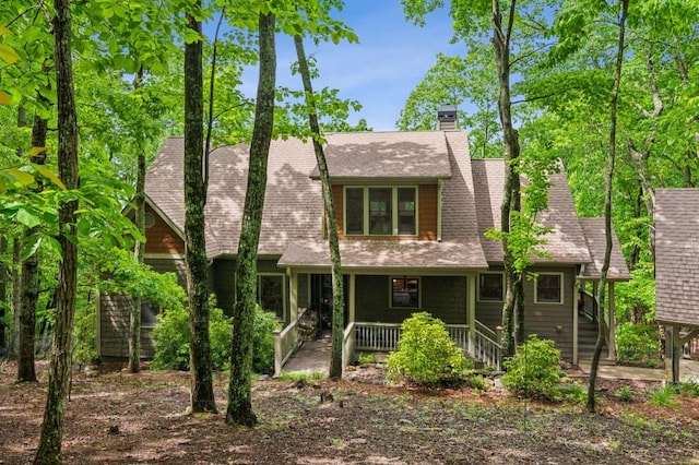 rear view of property with a porch, a chimney, a shingled roof, and stairway