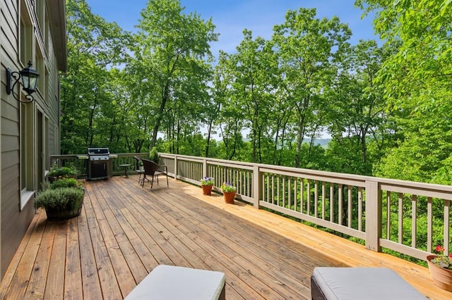 wooden deck featuring grilling area and view of wooded area